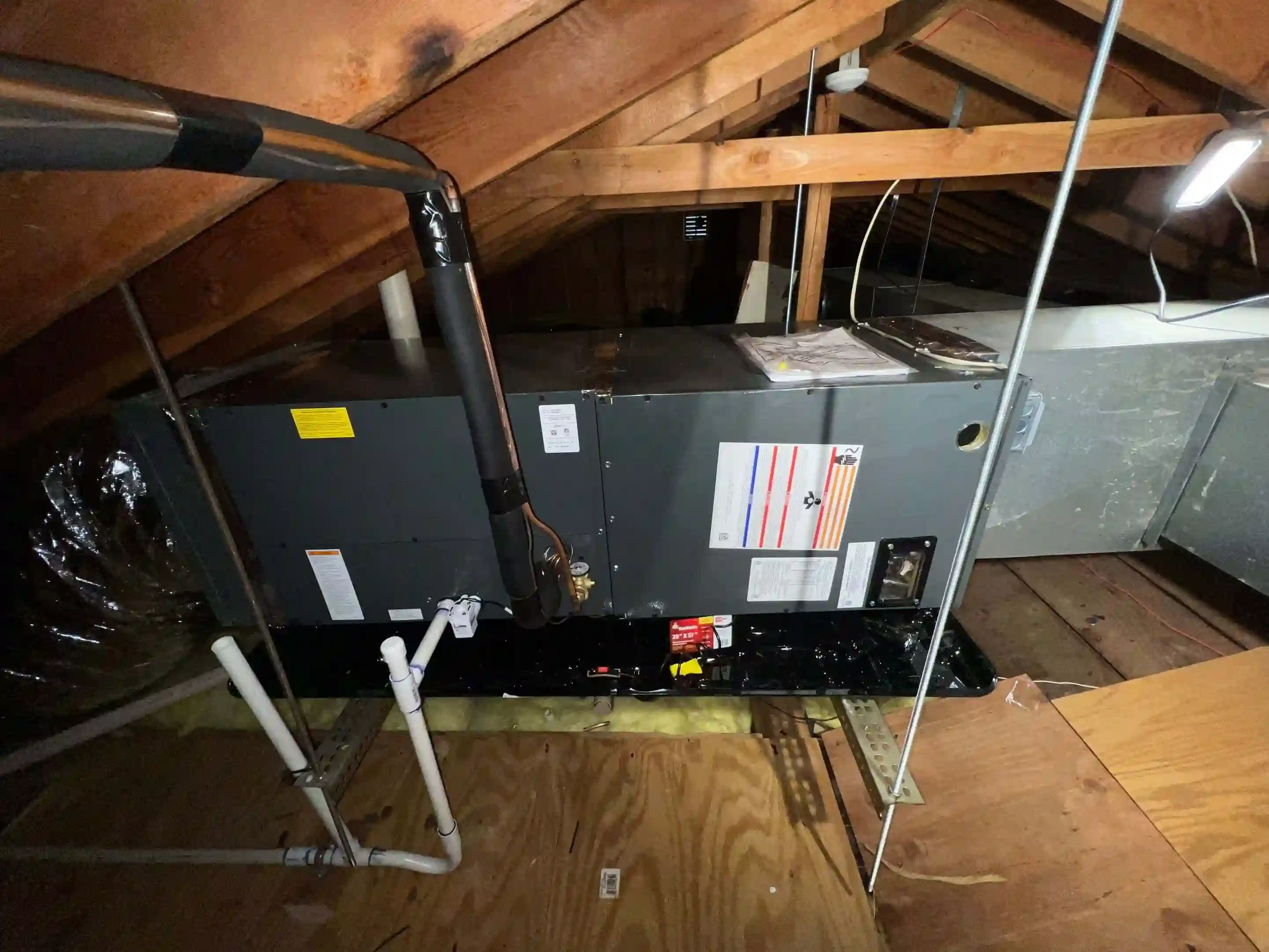 Attic air handler connected to ductwork and condensate piping