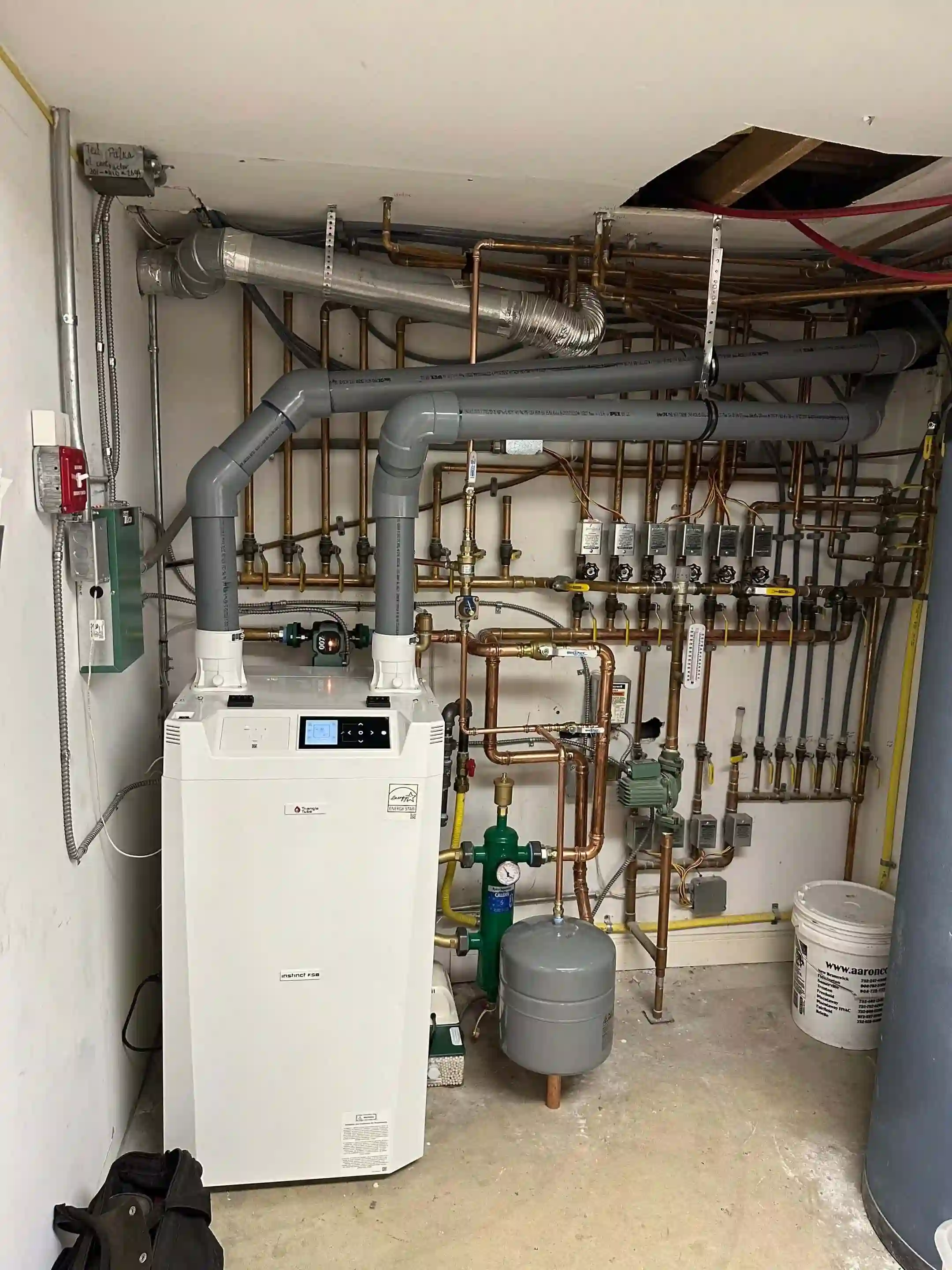Boiler room with wall-mounted boiler, venting, and manifold piping