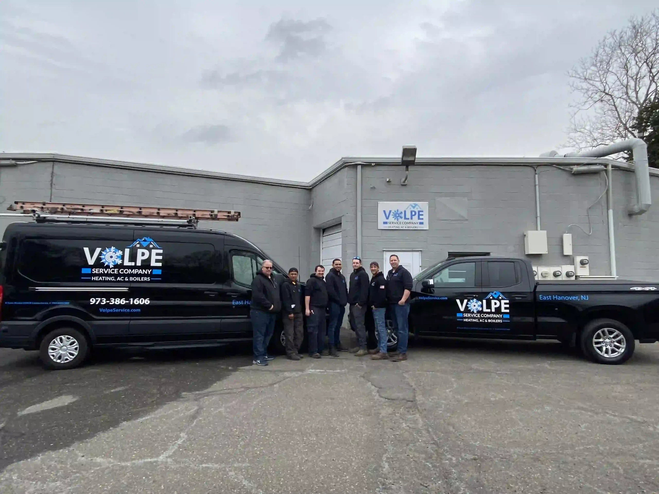 Volpe Service Company team and branded service vehicles outside the shop