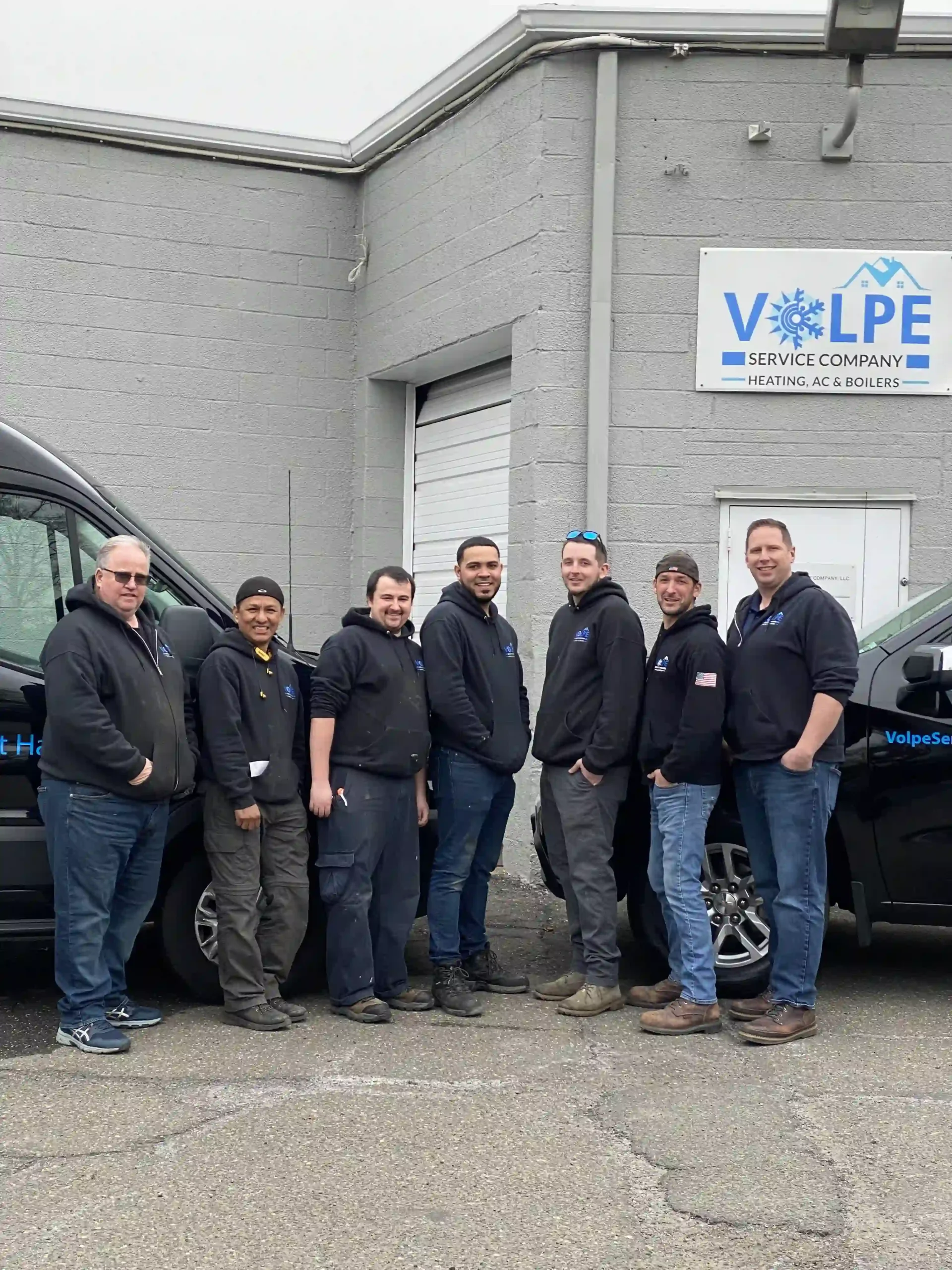 Volpe Service Company crew standing outside the shop with service vehicles