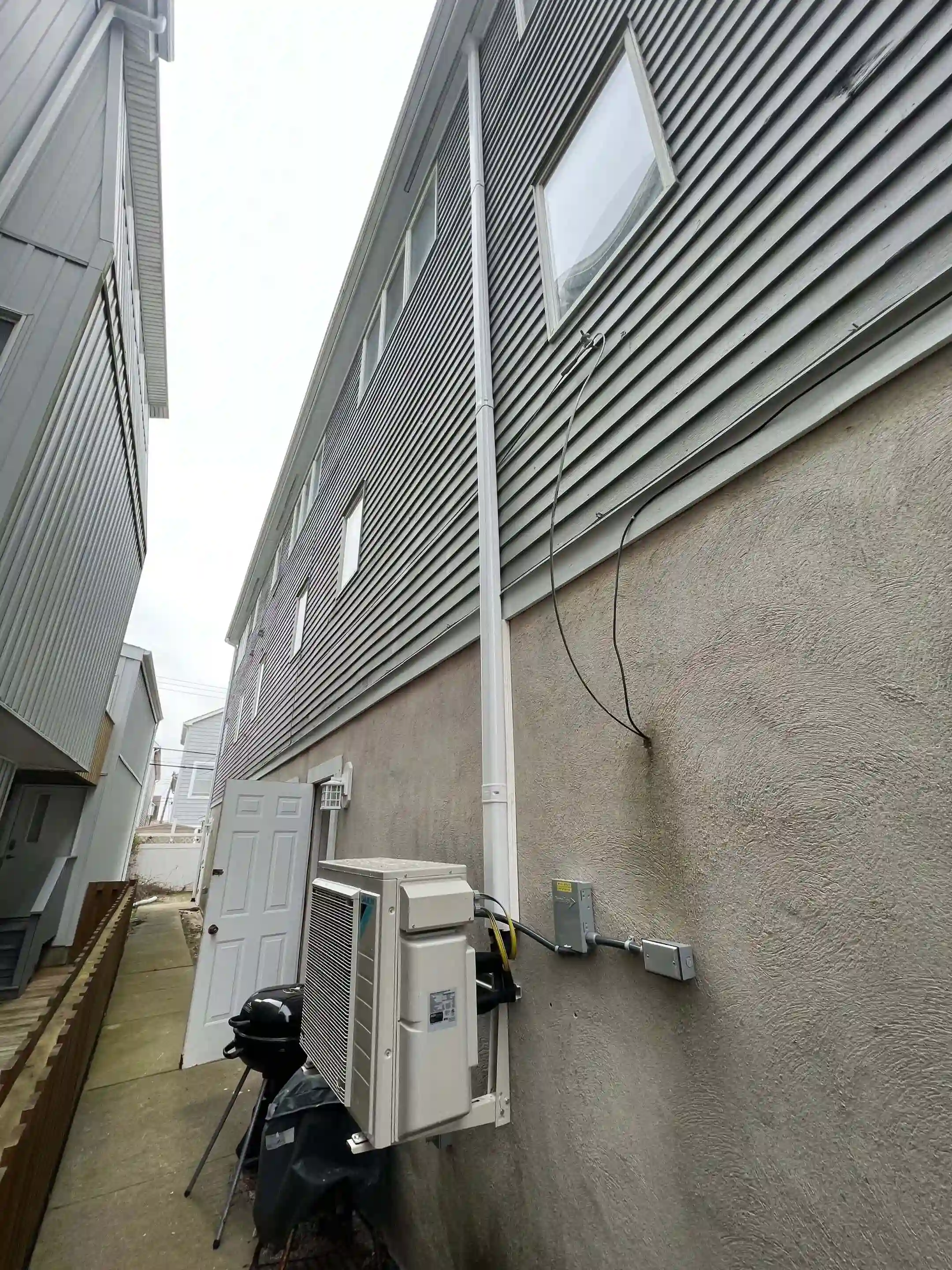 Outdoor ductless mini-split condenser with line set on a residential exterior wall