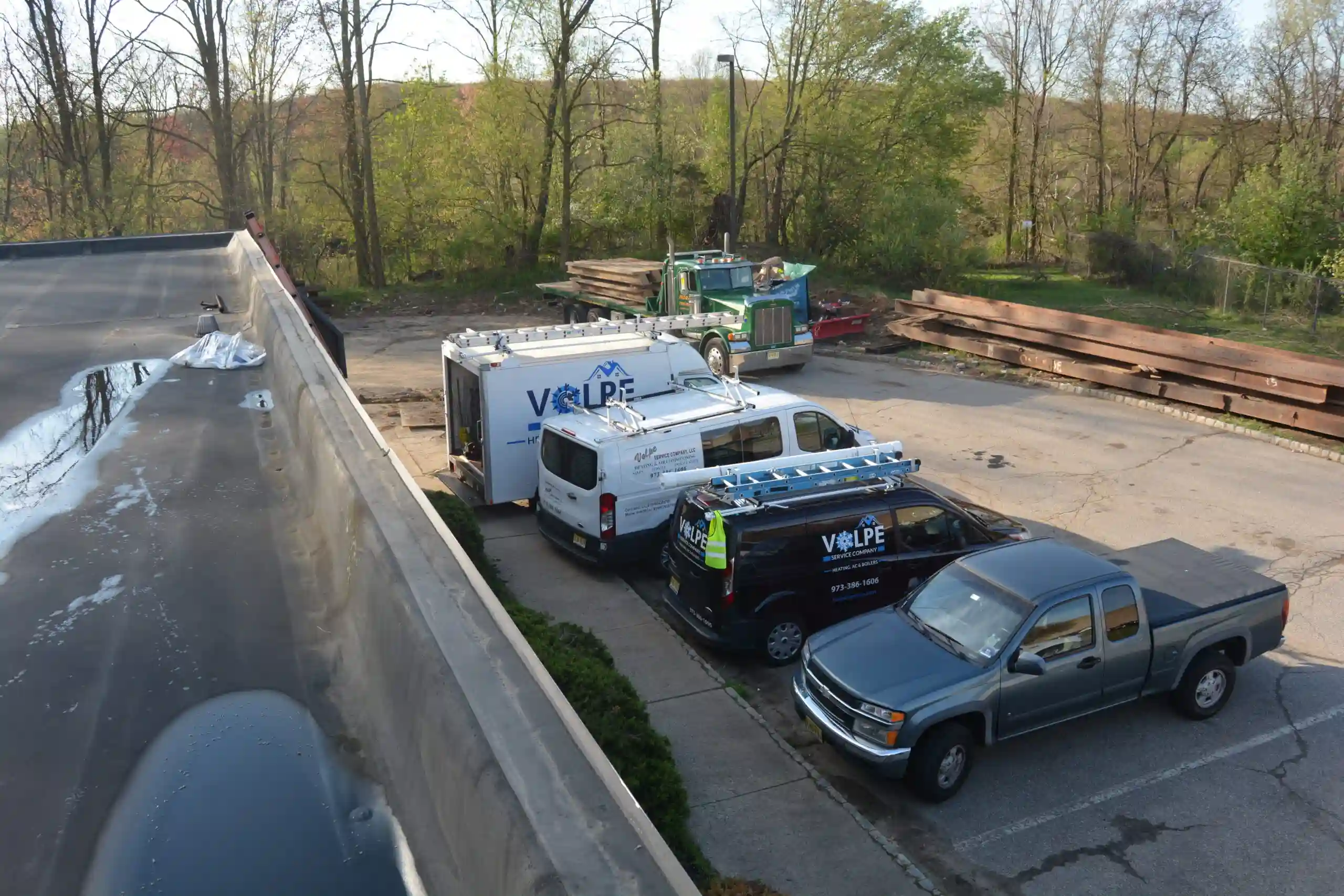 Volpe service vehicles and crane staged beside a commercial rooftop job
